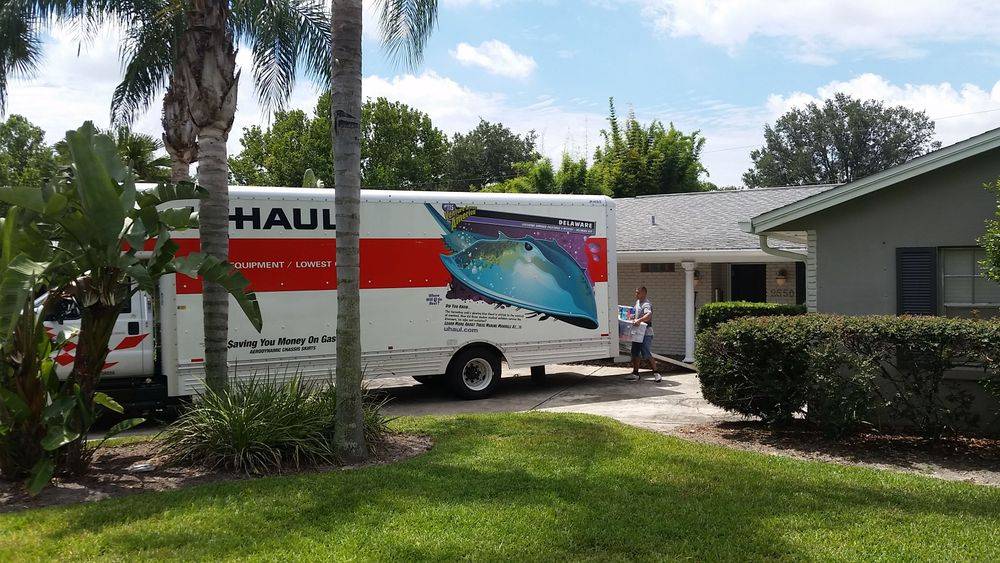 Uhaul truck parked in a drivewau of a home. Movers loading the uhaul.
