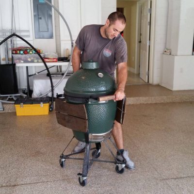 interior of a garage. Professional mover moving a green egg gril